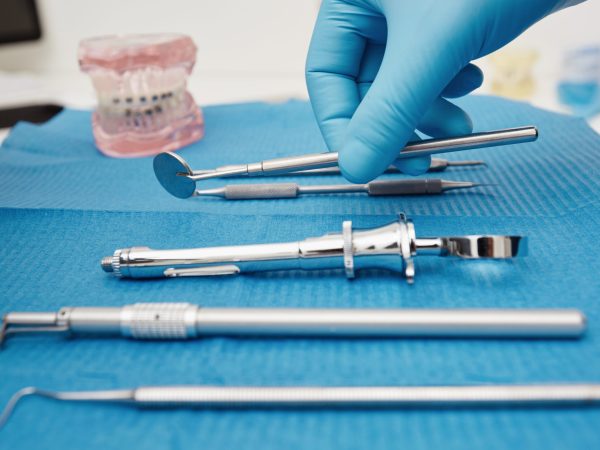 Set of metal medical equipment tools for teeth dental care. Doctor takes medical instruments. Hand of dentist reaching for dental instruments in a cabinet